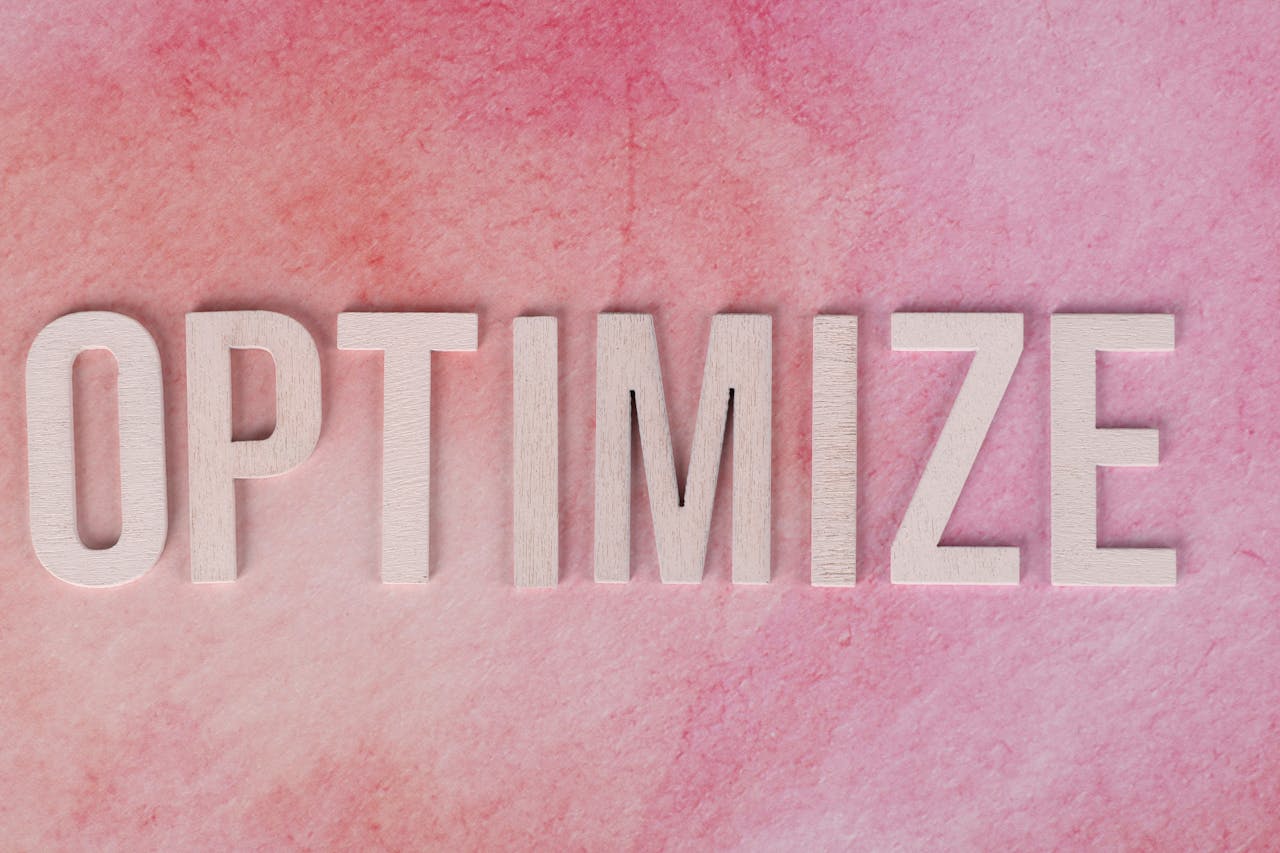 about-01 Creative display of the word OPTIMIZE on a pink textured surface.